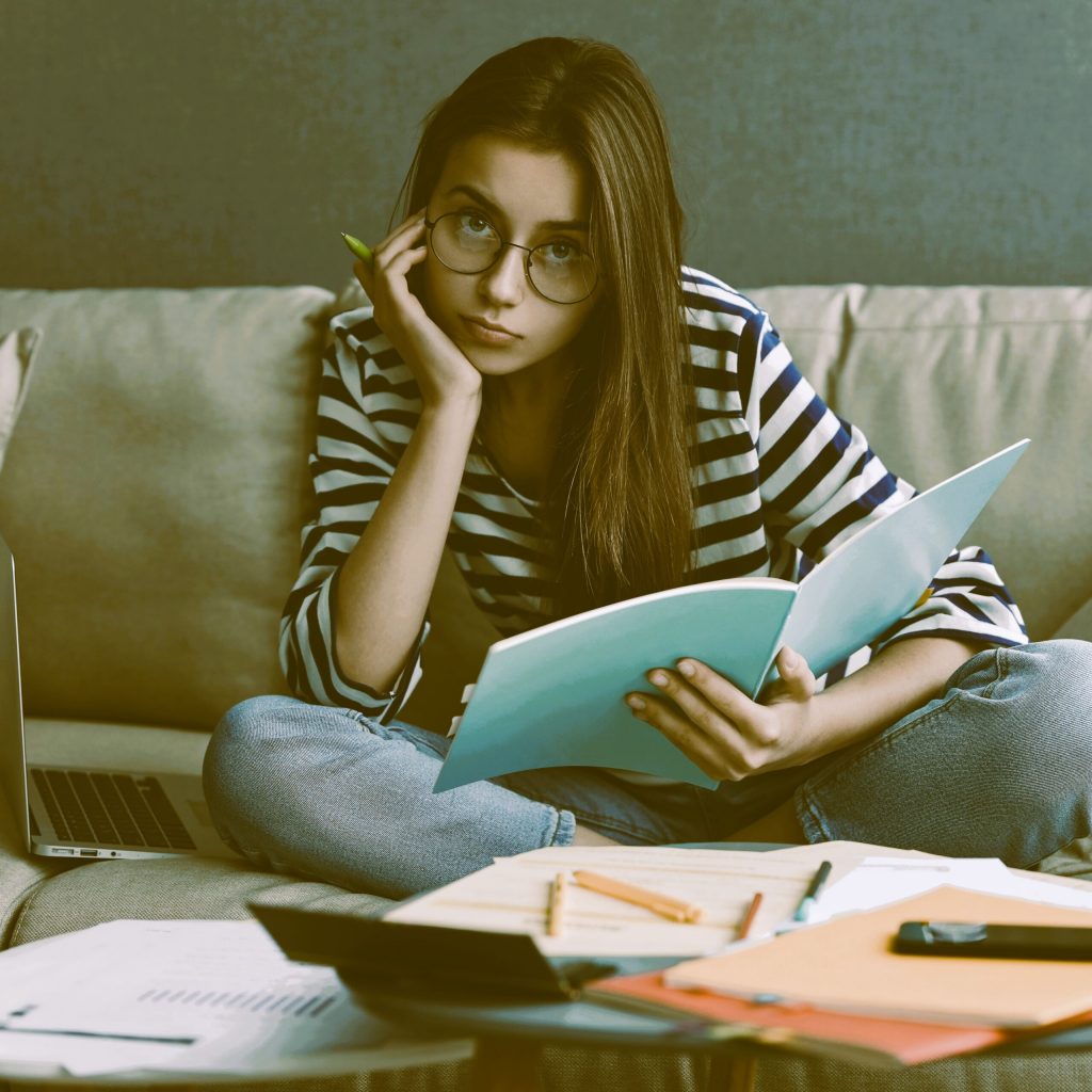 Grâce à la psychopédagogie, une lycéenne assis avec ses cours apprend à mémoriser. La psychopédagogie vise la métacognition et permet de savoir comment on apprend.